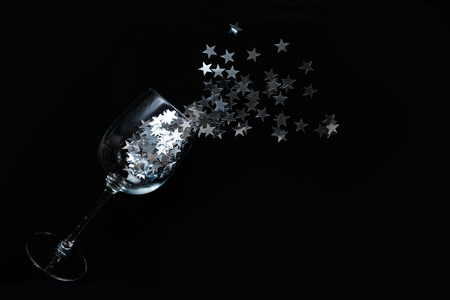 Wine glasses with silver star confetti on black background. Flat lay, top view. Holyday and celebration conceptの写真素材