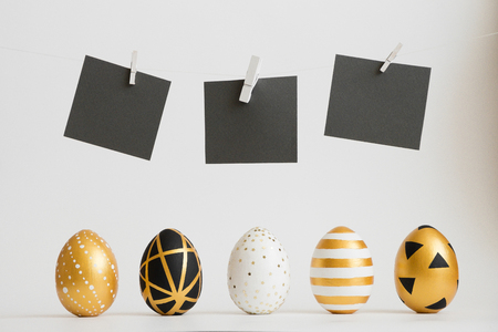 Easter golden decorated eggs stand in a row with black text stickers above them on white background. Minimal easter concept. Happy Easter card with copy space for text. Top view, flatlayの写真素材