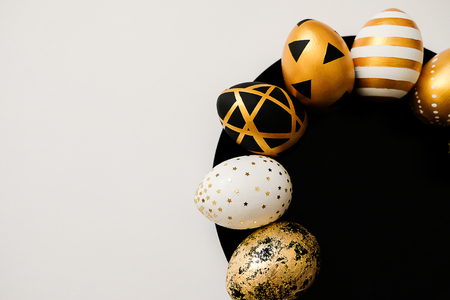 Stylish Easter golden decorated eggs on black plate isolated on white background. Trendy flat lay easter. Happy Easter card with copy space for text. Minimal easter conceptの写真素材