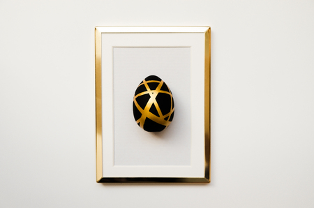 Frame with black  easter egg with copy space for text  isolated on white background. Minimal Happy Easter concept. Top view, flatlay.の写真素材