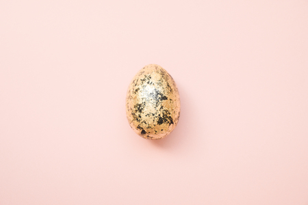 Easter decorated with golden potal egg on pastel pink background. Minimal easter concept. Happy Easter card with copy space for text. Top view, flatlay.の写真素材