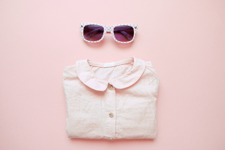 Set of summer childrens clothing on pink background. Baby girl fashion look with shirt and glasses.の写真素材