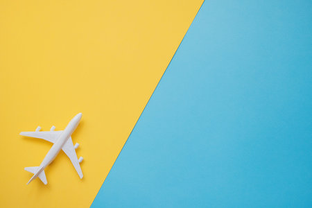 Flat lay design of travel concept with plane on blue and yellow background with copy space