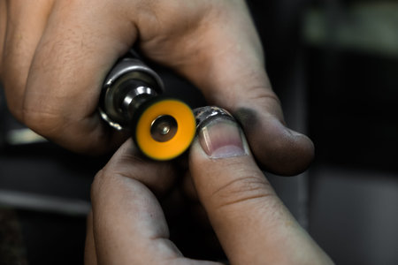 Hands of the jeweler polishes ring on the polishing machine. Goldsmith working on his workbench