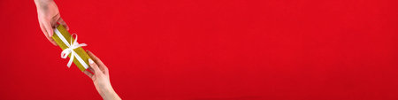 Golden gift box with white ribbon on red background for Valentines day. Space for text. Long wide...