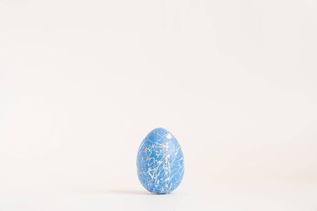 Easter golden decorated egg with paint splashes isolated on white background. Minimal easter concept. Happy Easter card with copy space for text Top view, flatlay.の写真素材