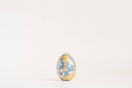 Easter golden decorated egg with golden potal isolated on white background. Minimal easter concept. Happy Easter card with copy space for text Top view, flatlay.の写真素材