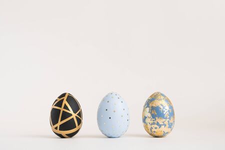 Three Easter golden decorated eggs on blue background. Minimal easter concept. Happy Easter card with copy space for text. Top view, flatlay.の写真素材