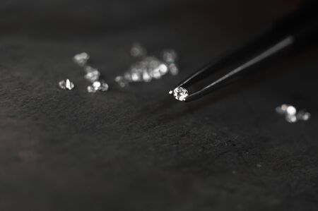 Diamond in tweezers. Craft jewelery, professional tools. Ring repairing. Macro shot.の写真素材