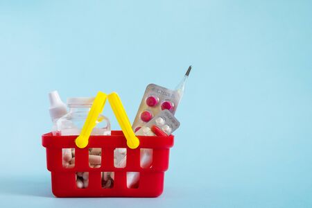 Buy and online shopping medicine concept. Various capsules, tablets and medicine in shopping basket on blue background. Creative idea for health care, health insurance and pharmaceutical company. Copy space.の写真素材