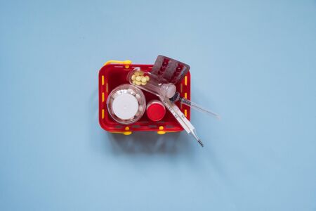 Buy and online shopping medicine concept. Various capsules, tablets and medicine in shopping basket on blue background. Creative idea for health care, health insurance and pharmaceutical companyの写真素材