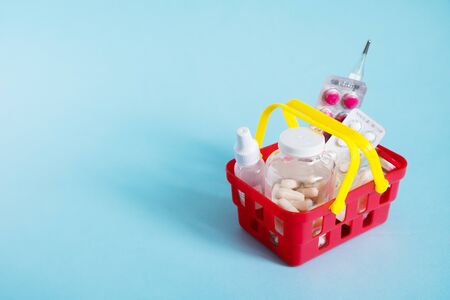 Buy and online shopping medicine concept. Various capsules, tablets and medicine in shopping basket on blue background. Creative idea for health care, health insurance and pharmaceutical company. Copy space.の写真素材