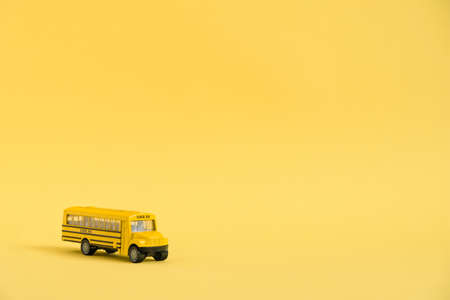 Back to school concept. Traditional yellow school bus on yellow background. Transfer to school. Yellow toy model school bus.の写真素材