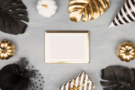 Modern Halloween background with gold ans black pumpkins, monstera, stars confetti and golden frame. Halloween party invitation card mockup. Flat lay, top view, copy space.の写真素材