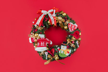 Beautiful Christmas hand made rustic wreath on red background. Made with pine cones, balls and leafsの写真素材