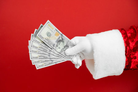 Santa Claus hand holding money on red background. Hand with cash.の写真素材