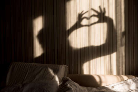 Woman making heart shadow with her hands on the wall. World mental health day, hope and love. Valentines 14 Februaryの写真素材