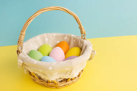 Basket with Easter colorful eggs on yellow blue background. Happy Easter conceptの写真素材