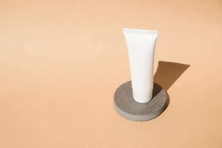 Beauty products display, grey stone podium on pastel beige background for skin care product presentation. Composition with a cosmetic white tube with copy space for text or designの写真素材