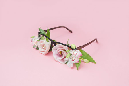 Summer concept of beach sunglasses with flowers instead of glasses on a pink background. Summer vacation and enjoyment minimal concept. Woman accesory.の写真素材