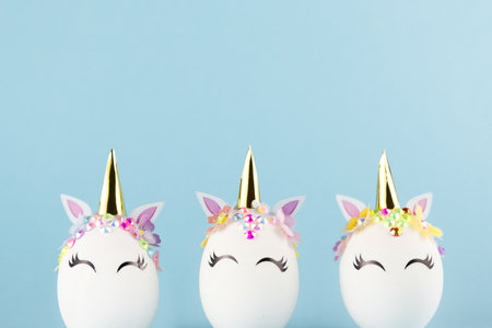 Easter unicorn eggs isolated on blue background. Happy easter banner. Kids activity inspiration. Greeting card or poster. Copy space for textの写真素材
