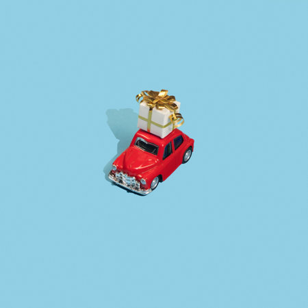 Golden gift on roof red toy car on blue background. Minimal Happy New Year concept.の写真素材