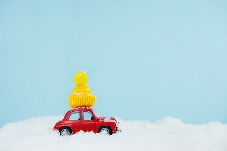 Christmas red car with knitted yellow hat in a snowy landscape. Space for text. Happy New Year card conceptの写真素材