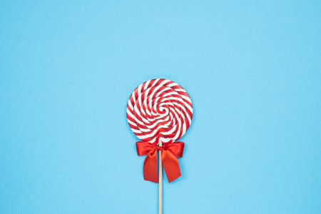 Colorful lolipop on blue background, wooden stick, red and white spiral, childhood sweets, Christmas conceptの写真素材