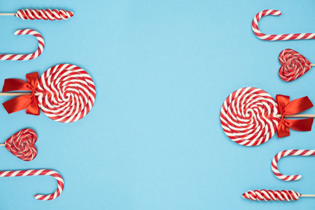 Christmas red striped candy canes and lollipops on blue background. Merry Christmas sweets and Happy New Year concept. Flatlay, copy spaceの写真素材
