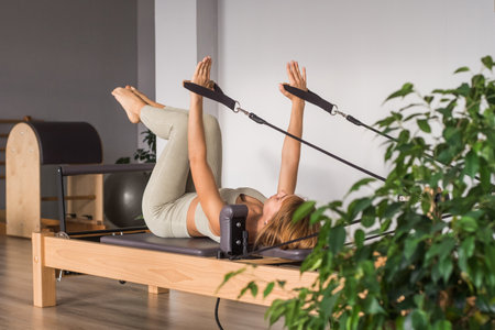 Woman training pilates on the reformer bed. Reformer pilates studio machine for fitness workouts in gym. Fit, healthy and strong authentical body. Fitness conceptの写真素材