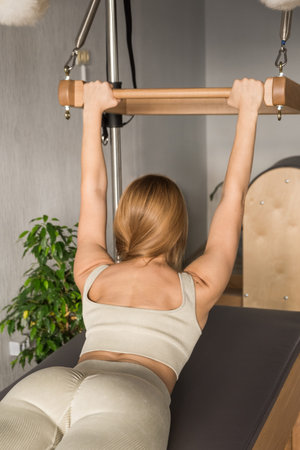 Pilates fitness trainer doing back strengthening exercises on in pilates studio. Balanced Body...