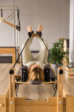Woman training pilates on the reformer bed. Reformer pilates studio machine for fitness workouts in gym. Fit, healthy and strong authentical body. Fitness conceptの写真素材