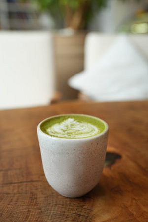 Top view of matcha green tea latte with a latte heart art on wooden table cafe background