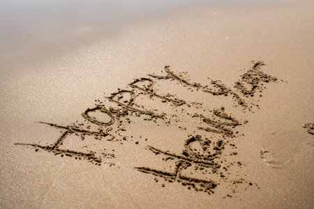 A Happy New Year Message Beautifully Written in the Soft Sand on the Serene Beach