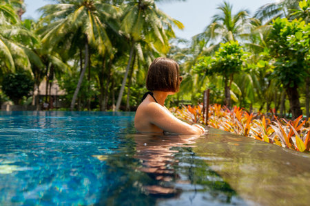 Enjoy a delightful experience of relaxing in a tropical pool surrounded by swaying palm trees