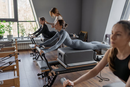 Womens doing Swan exercise on Pilates Reformer for the chest and back muscles, focusing on flexibility, strength, and control with determinationの写真素材