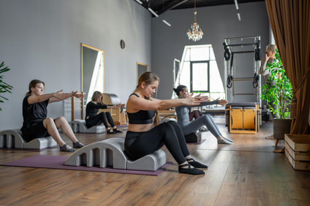 Group of women doing exercises on back spine corrector. Reformer pilates studio machine for fitness...