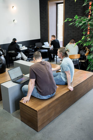 Programmers discussing over laptop working at startup. Office, business and friends together in...