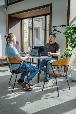 Programmers discussing over laptop working at startup. Office, business and friends together in...