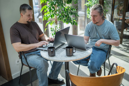 Two It Software engineers working on project and programming in coffee shop. Business people...