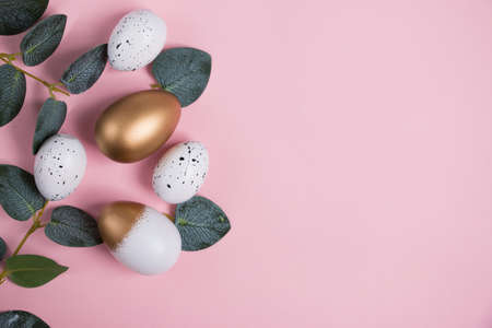 Easter eggs with green eucalyptus branches on a pink background. holiday concept. happy easter greeting cardの写真素材