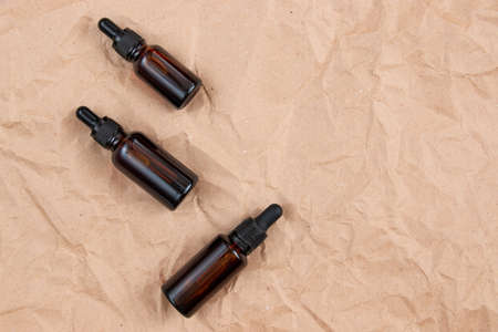 Cometic bottles made of amber glass on crumpled craft paper. Skin care product packaging design. spa concept.の写真素材
