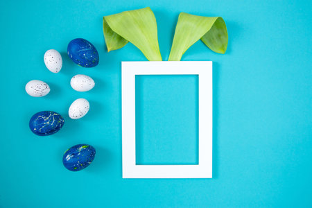 Happy Easter minimal concept. Bunny face made from natural green leaves on a blue background. flat...
