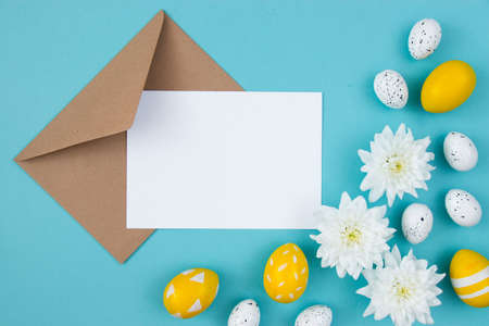 White flowers and painted Easter eggs on a blue background. Festive floral concept with clean text space. flat lay. view from above.の写真素材