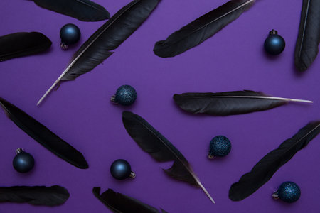 Black feathers and blue Christmas balls on a purple background. christmas concept.の写真素材