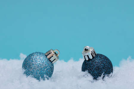 Christmas balls on snow and blue background. The minimalistic style of the New Year's card.の写真素材