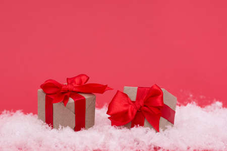 Christmas boxes with gifts on snow and pink background. The minimalistic style of the New Year's card.の写真素材