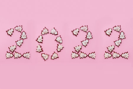 Number 2022 from wooden Christmas trees isolated on pink background.