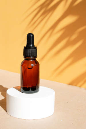 A cosmetic bottle with an amber glass dropper sits on a concrete pedestal. natural beauty products. Mineral organic oil. Empty bottle for skin care. hard sunlight.の写真素材