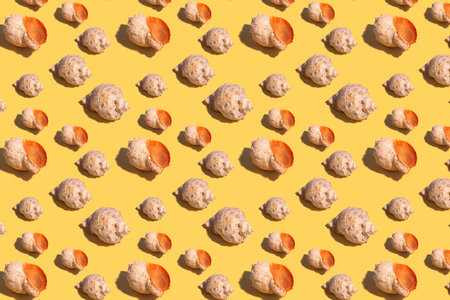 Seamless regular pattern with seashells on a yellow background. hard light. Summer vacation and travel concept.の写真素材